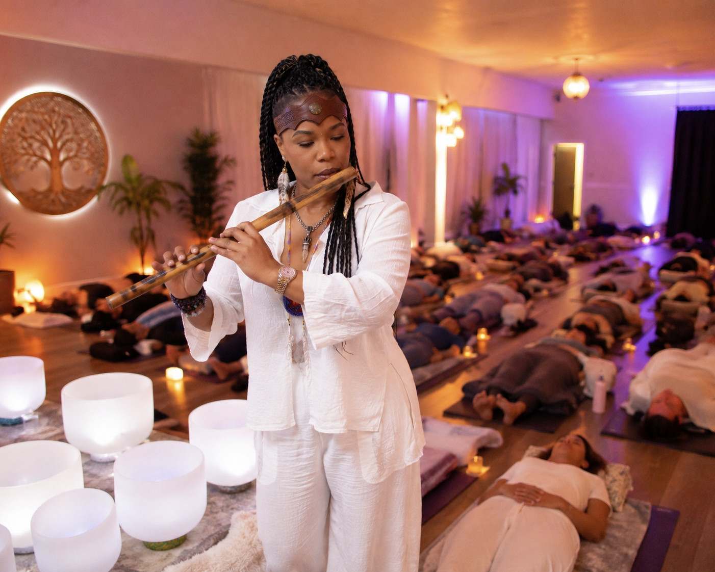 Shaman Yawna Shakti facilitating a hospitality wellness experience with flute and singing bowls