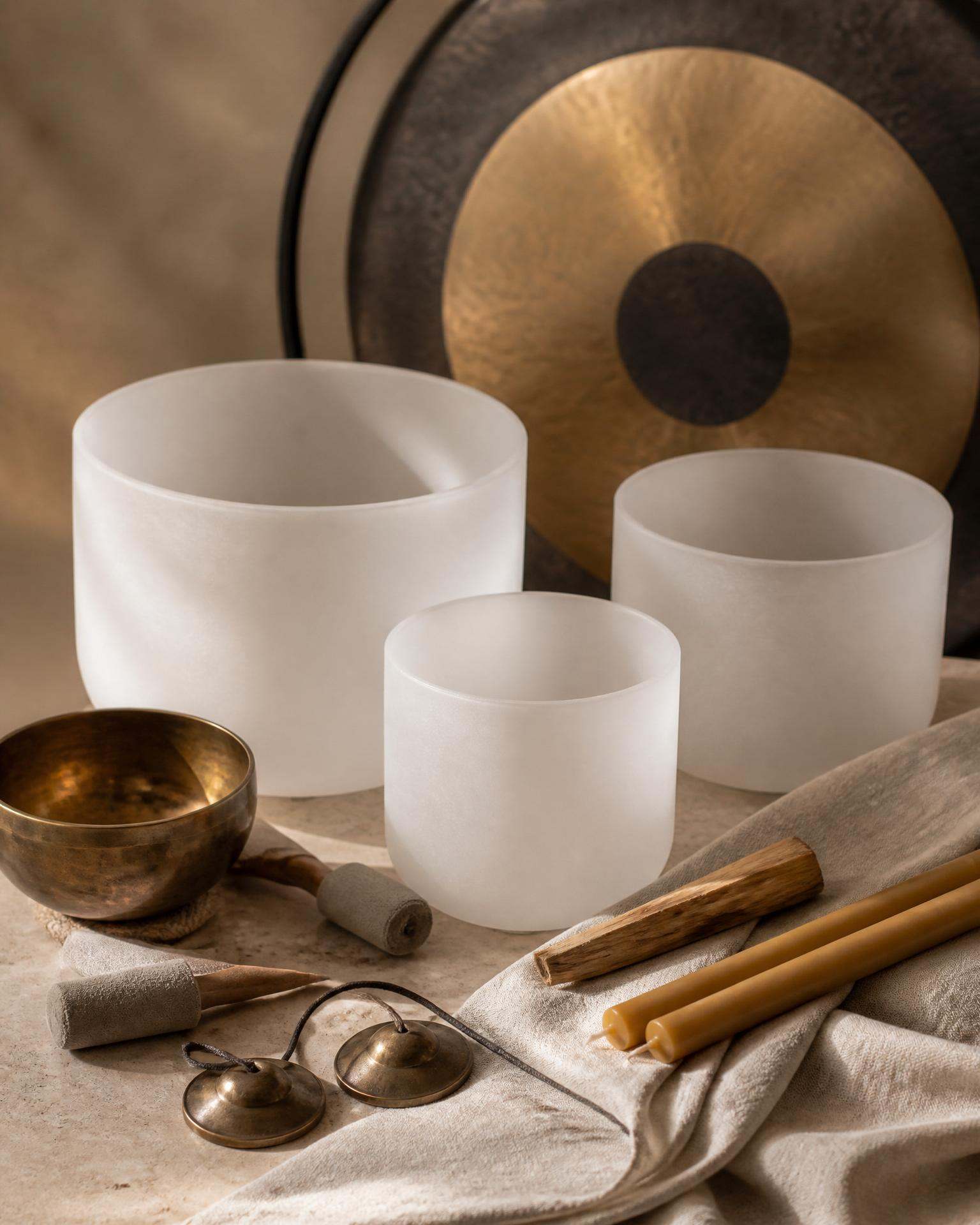 Three quartz crystal singing bowls on travertine with palo santo and a single ranunculus