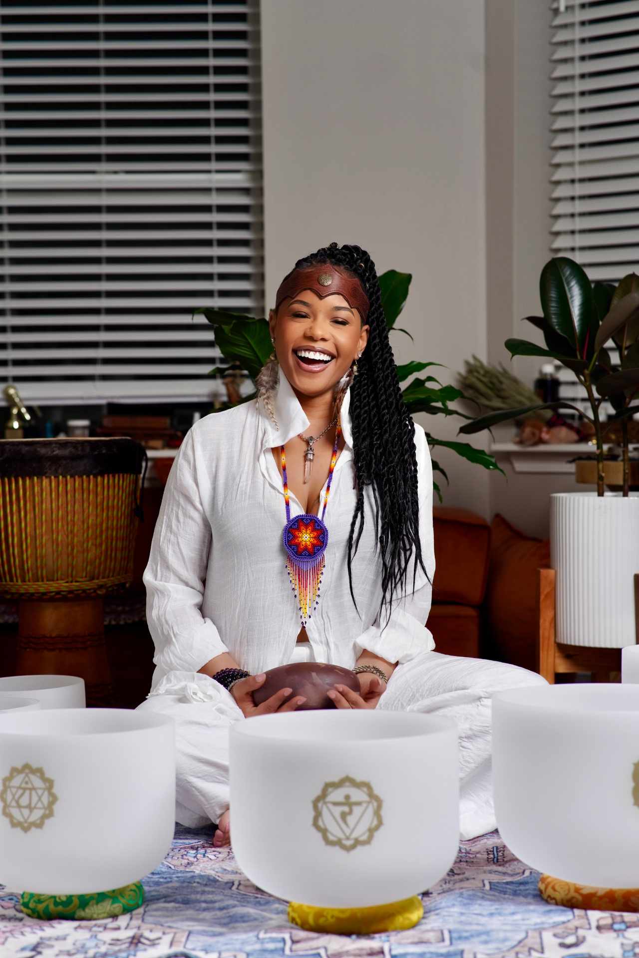 Shaman Yawna Shakti seated among her crystal singing bowls wearing a Huichol beaded necklace from her study in Mexico